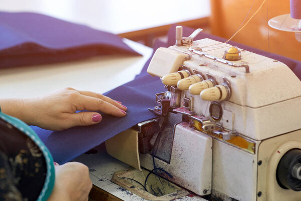 Tailor-made hands sew fabrics on the sewing machine.