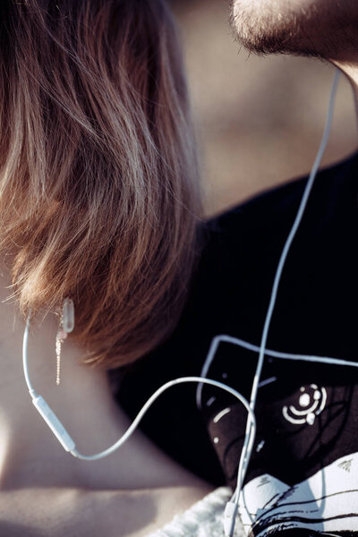 Крупный план двух любящих подростков, которые слушают музыку через хэдфон
