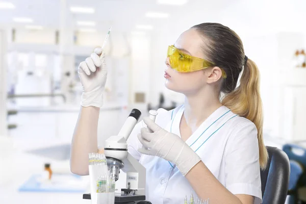 Fechar-se de uma bela assistente de laboratório menina em óculos com um micr — Fotografia de Stock