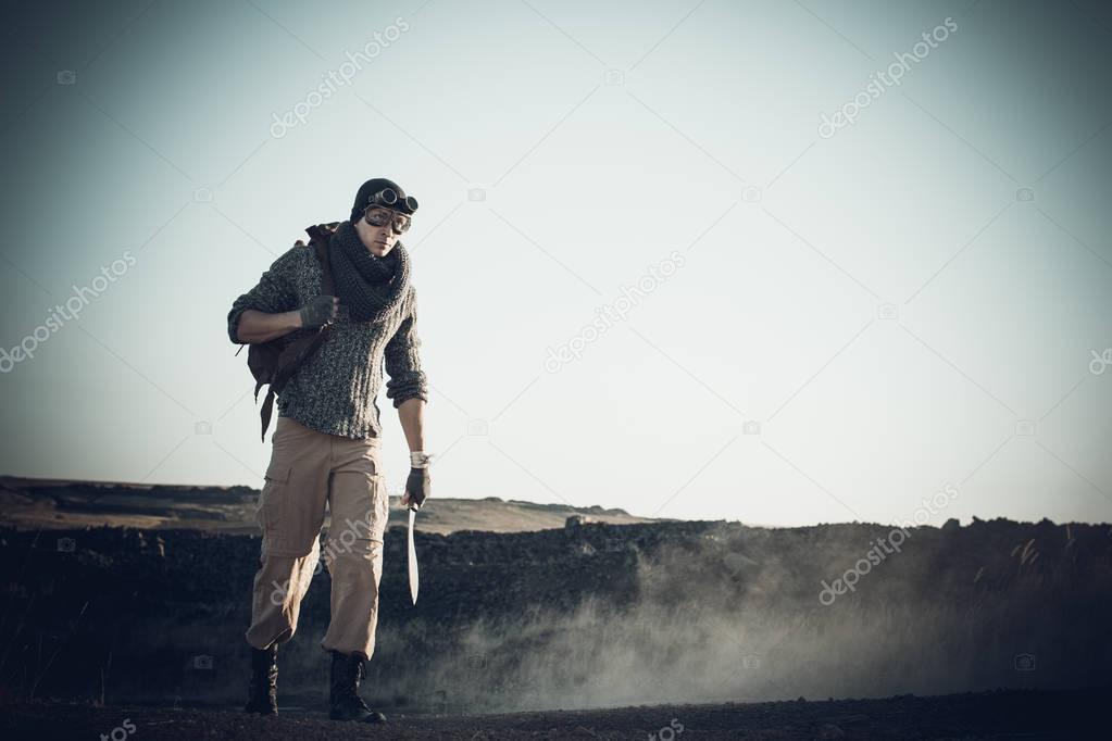 A lonely warrior walks along the road in a suit and goggles surv