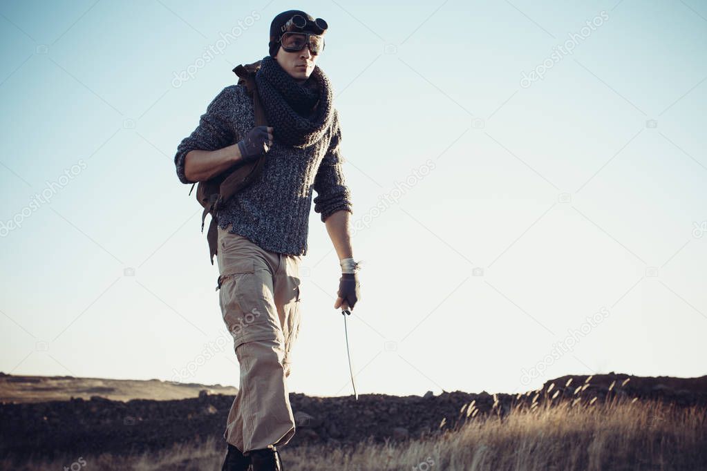 A lonely warrior walks along the road in a suit and goggles surv