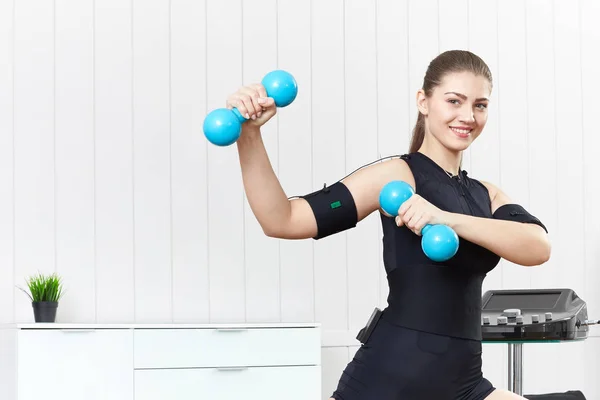 A young girl is engaged in fitness with blue dumbbells