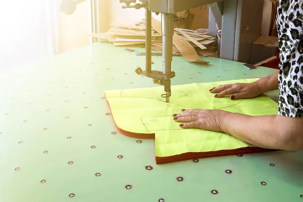 Female worker on a sewing manufacture uses electric cutting fabr — Stock Photo, Image