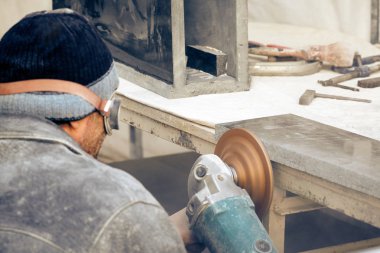 İşçi granit taş bir öğütücü ile işler.. 