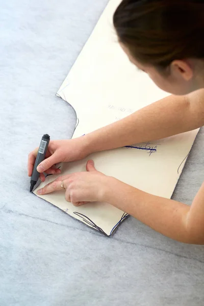 Ein Schneidmädchen arbeitet an einem großen Tisch mit einem Marker, der das f markiert — Stockfoto