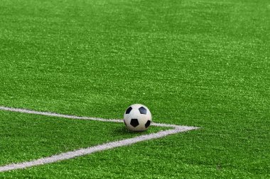 Yeşil bir futbol üzerindeki beyaz köşe işaretleri tarafından çerçeveli bir futbol topu