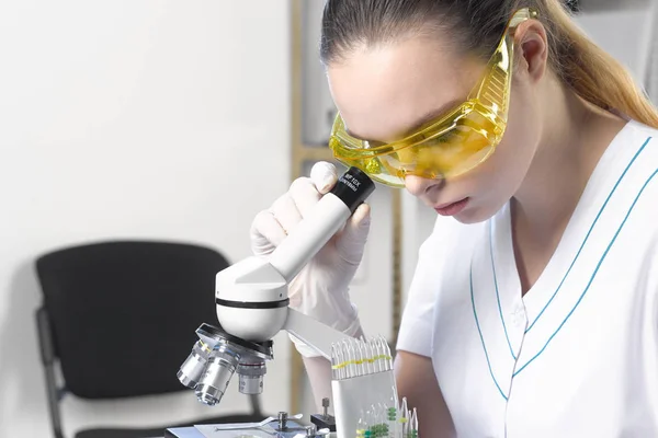 Uma estudante assistente de laboratório em óculos de proteção trabalha com — Fotografia de Stock