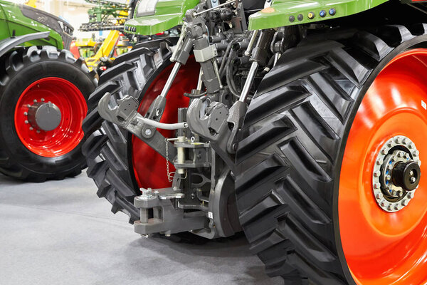 Rear view of the big black rubber wheels and the hydraulic system of an agricultural tractor or combine.
