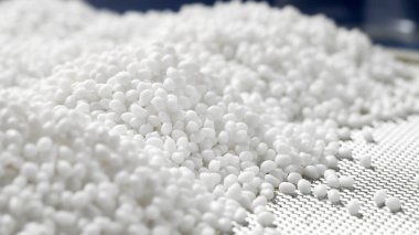 Mavi arka plandaki bir laboratuarda beyaz plastik polimer granüle yakın plan..