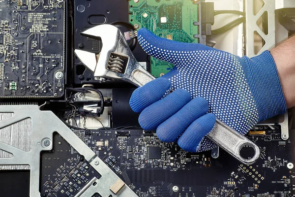 Engineer hand with wrench and personal computer board open for diagnosis and repair or upgrade. Conceptual image.