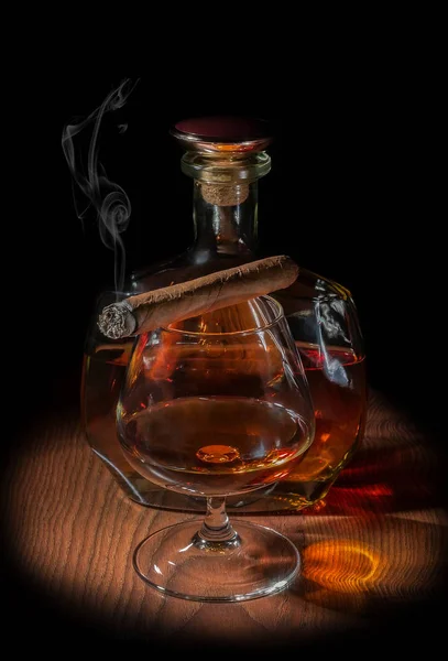 A glass of cognac with a cigarette and a bottle of cognac — Stock Photo, Image