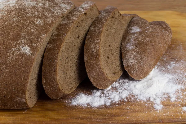 Pane scuro tagliato su una tavola con farina — Foto Stock