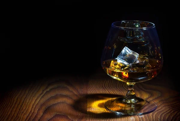 Glass of cognac with ice cubes — Stock Photo, Image
