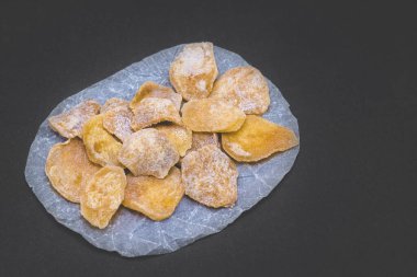 Siyah arka planda dilimlenmiş zencefil şekeri. Vejetaryen tatlıları. Detokslu tatlı.