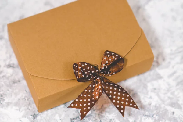 Craft gift box with a brown ribbon in white polka dots on grunge background. Surprise and gift.