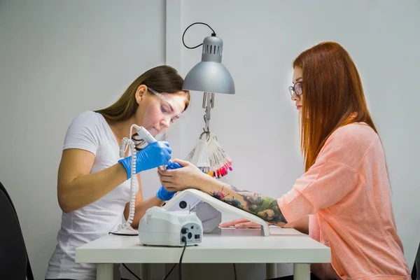 Kvinde i en neglesalon modtager en manicure af en kosmetolog - Stock-foto