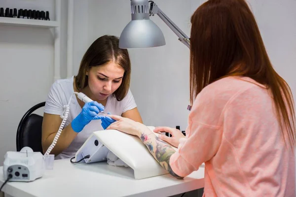 Manicura de hardware en un salón. Manicurista está aplicando taladro de lima de uñas eléctrica —  Fotos de Stock