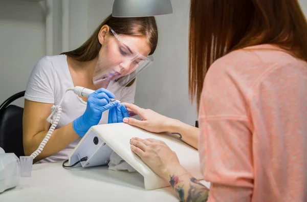 Mujer en un salón de uñas recibiendo una manicura por una esteticista —  Fotos de Stock