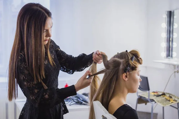 Cabeleireiro profissional fazendo penteado para jovem mulher bonita com cabelo longo — Fotografia de Stock