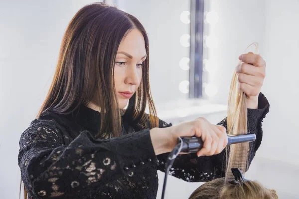 Schöne junge Frau lässt sich im Schönheitssalon die Haare glätten — Stockfoto