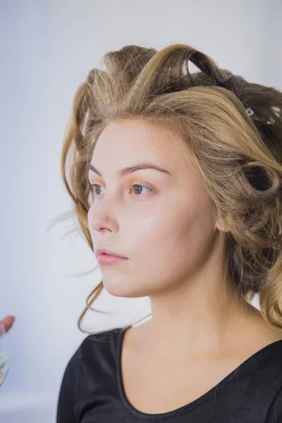 Makyöz, kadının yüzüne sıvı tonal fondöten uyguluyor.