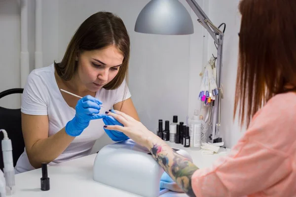 Manicura tratando al cliente en el salón de belleza - pintura en la uña —  Fotos de Stock