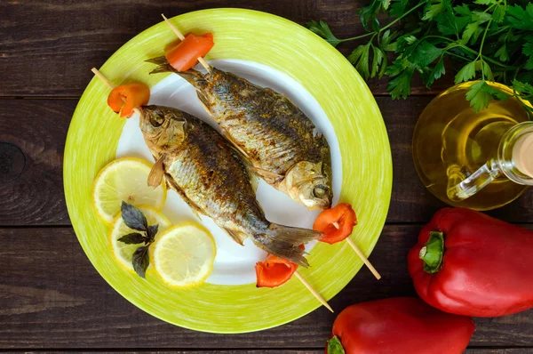 Gebakken vis (carp) op spiesen met stukjes peper en citroen. Het bovenaanzicht — Stockfoto