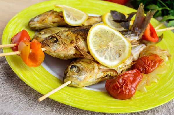 Gebakken vis (karper) op spiesjes met stukjes paprika, zongedroogde tomaten en citroen — Stockfoto