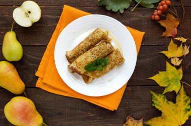 Beyaz bir tabak ta karamelize armut ile kokulu tatlı krep. Üst görünüm
