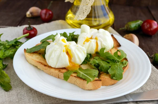 Вареные яйца в мешке (вареные) на хрустящих тостах и зеленых листьях рукколы. Диетический завтрак . — стоковое фото