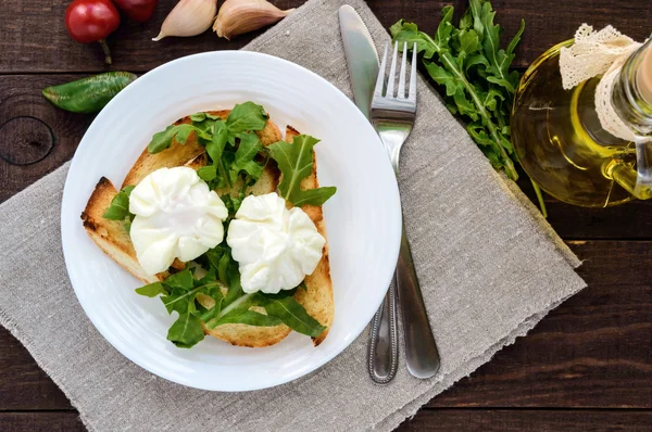 Uova sode in un sacchetto (in camicia) su pane tostato croccante e foglie di rucola verde . — Foto Stock