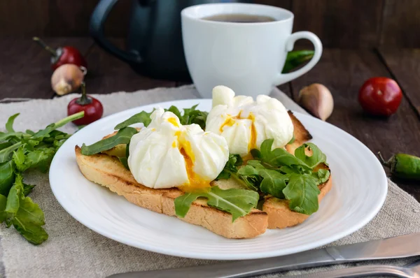 Вареные яйца в пакете (вареные) на тосте и хрустящих зеленых листьях рукколы и чашке чая. Диетический завтрак . — стоковое фото