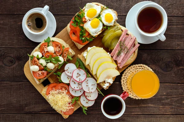 De nombreux types de sandwichs, bruschetta et thé, café, jus de fruits frais pour un petit déjeuner en famille . — Photo