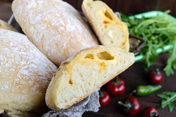 Ciabatta peynir doldurma ile-İtalyan beyaz ekmek koyu ahşap arka plan üzerinde fırından yeni çıkmış. Sandviç hazırlık için. — Stok fotoğraf