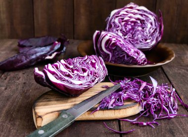 Kırmızı lahana kesme koyu ahşap arka plan üzerinde bir bıçakla parçalara. Sebze yemekleri yemek için madde.