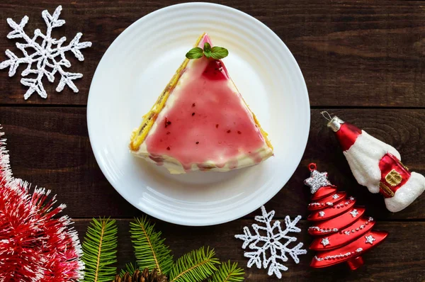 Sponge cake with a layer of banana, milk cream and cranberry syrup on a white background. Holiday dessert. Christmas theme. — Stock Photo, Image
