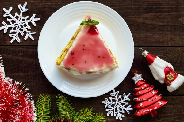 Biskuitteig mit einer Schicht Banane, Milchcreme und Preiselbeersirup auf weißem Hintergrund. Urlaubsdessert. Weihnachtsthema. — Stockfoto