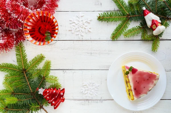 Biskuitteig mit einer Schicht Banane, Milchcreme und Preiselbeersirup auf weißem Hintergrund. Urlaubsdessert. Weihnachtsthema. — Stockfoto