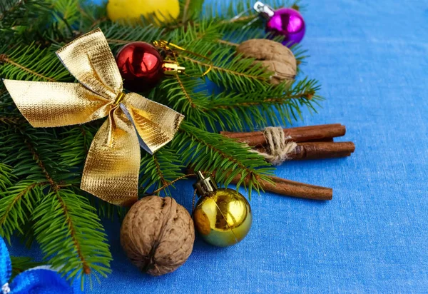 Рождественский фон Ветви ели украшены красочными украшениями, орехами и корицей на голубой салфетке . — стоковое фото