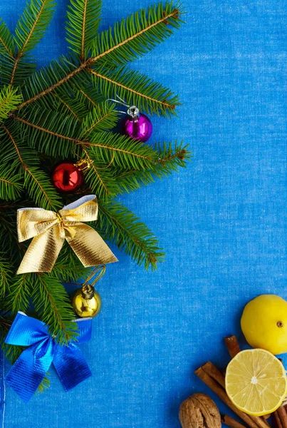 Рождественский фон Ветви ели украшены красочными украшениями, орехи, корица, лимон на голубой салфетке. Вид сверху . — стоковое фото