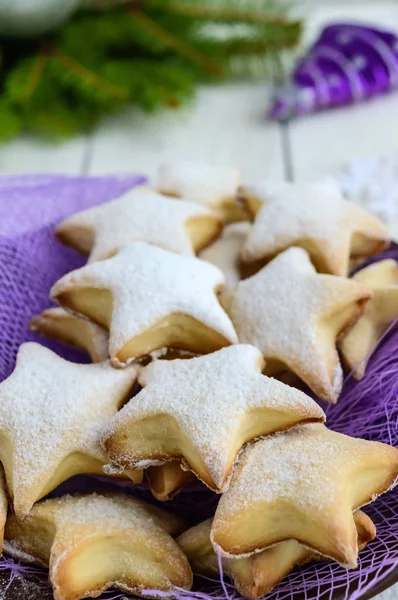 Hausgemachte Vanilleplätzchen in sternförmiger Dekoration mit Puderzucker auf einer lila Serviette. Nahaufnahme — Stockfoto