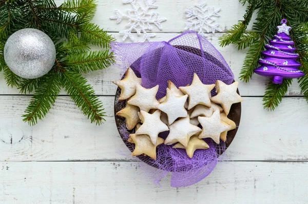 Ramas de abeto verde y decoración con arcos dorados y galletas en forma de estrella sobre un fondo blanco. Tema navideño. La vista superior . — Foto de Stock