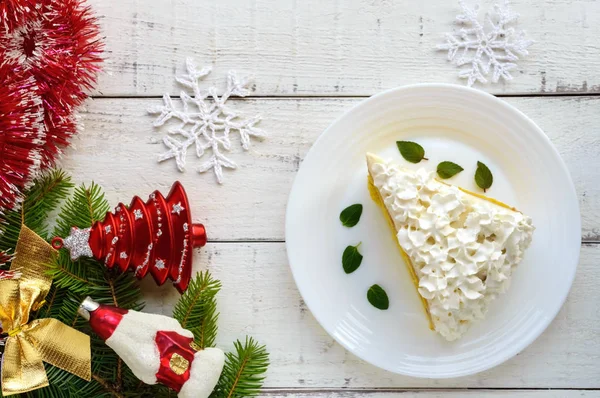 Ein großes Stück delikater Biskuitkuchen, der Luftcreme verziert. Festliches Dessert auf weißem Hintergrund. Weihnachten, Silvester zu feiern. die Ansicht von oben — Stockfoto