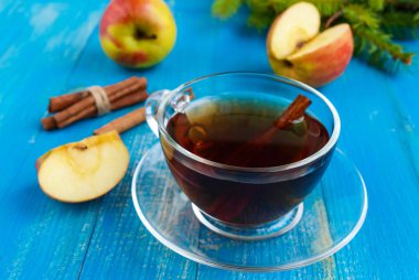 Elma ve tarçın bir mavi ahşap arka plan şeffaf cam fincan ile şenlikli vitamini çay kış ısıtır.