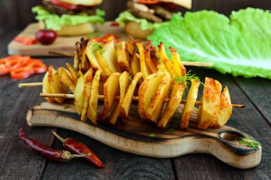 Patates daireler baharat (ev yapımı cips) ile bir bambu şiş üzerinde pişmiş. Aperatifler bira koyu ahşap arka plan için. Yakın çekim.