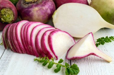Beyaz ahşap bir masa üzerinde turp çeşitli türleri. Salata için yararlı vitaminler madde. Ön planda bir kırmızı turp kesme dilimleri