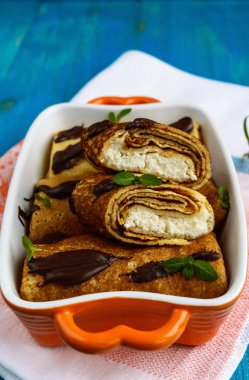 Lor, çikolata, üzerinde mavi bir arka plan dekorasyon nane yaprakları ile krep. Dikey Görünüm