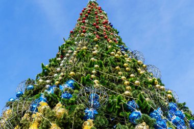 Sokakta duran şenlikli bir noel ağacı. Aşağıdan mavi gökyüzüne karşı görüntüle.