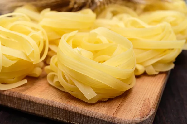 Pasta tagliatelle in the form of nests onthe wooden background.  Close-up. — Stock Photo, Image