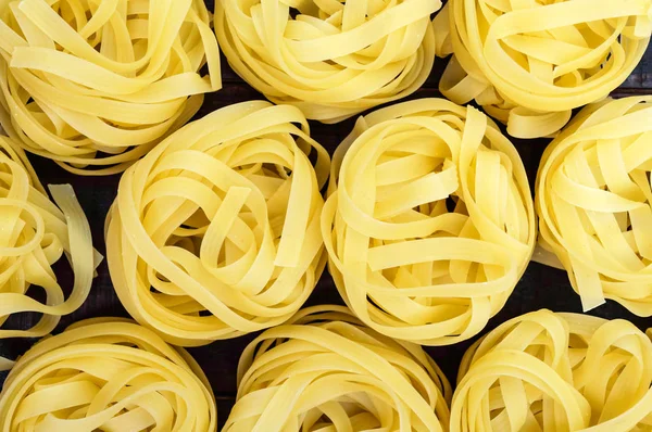 Pasta tagliatelle in the form of nests. Food background. The top view. Close-up. — Stock Photo, Image